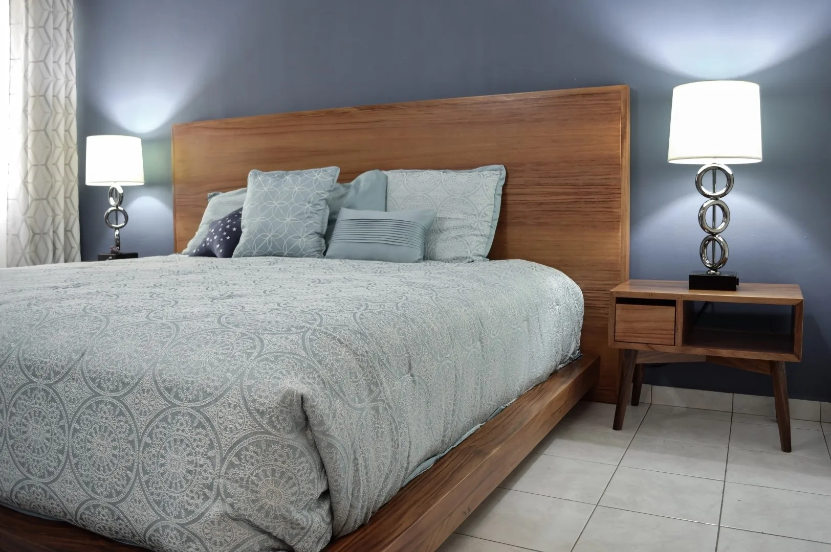 bed base, bedroom with mat on the floor, clay pot in the background, wooden credenza and mirror.